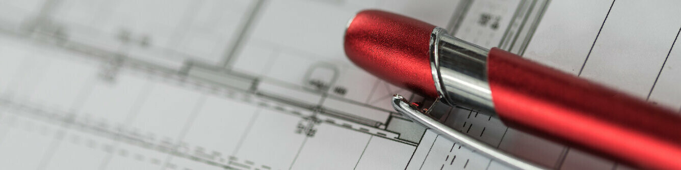 Rød PREFA-penn ligger på en plan