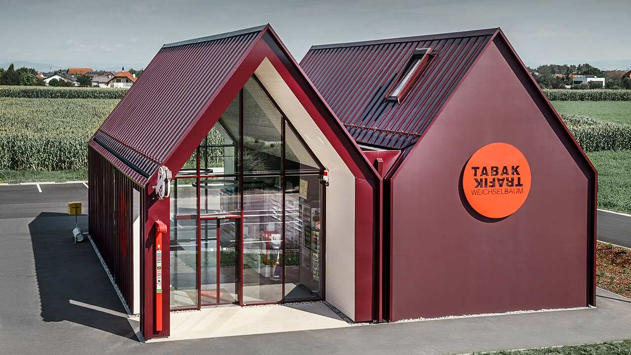 Moderne tobakkskiosk i St. Valentin med saltak uten takutstikk og bygningskledning i rød aluminium