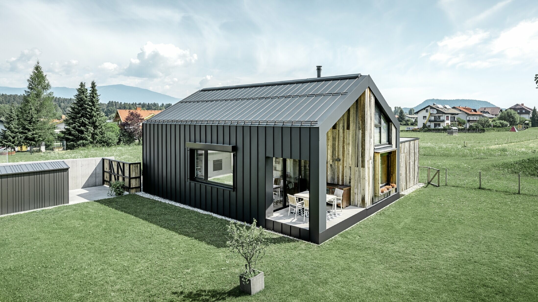 Enebolig med saltak, tak og fasade er dekket med PREFALZ fra PREFA i P.10 antrasitt. Platene på takflaten går også videre over fasaden. En del av fasaden er kledd med barskt treverk.