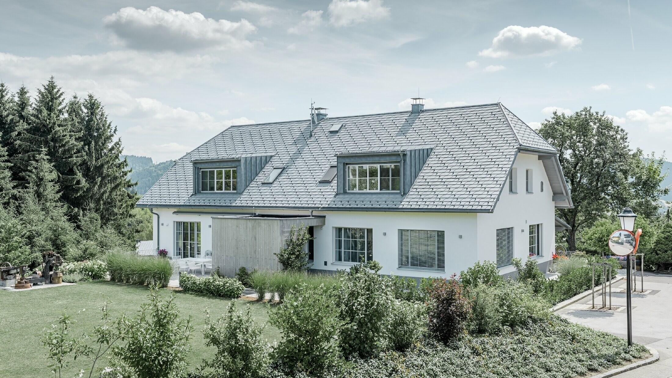 Takrenovering av et halvvalmtak med den lette PREFA takshingelen i steingrå med to kvister.