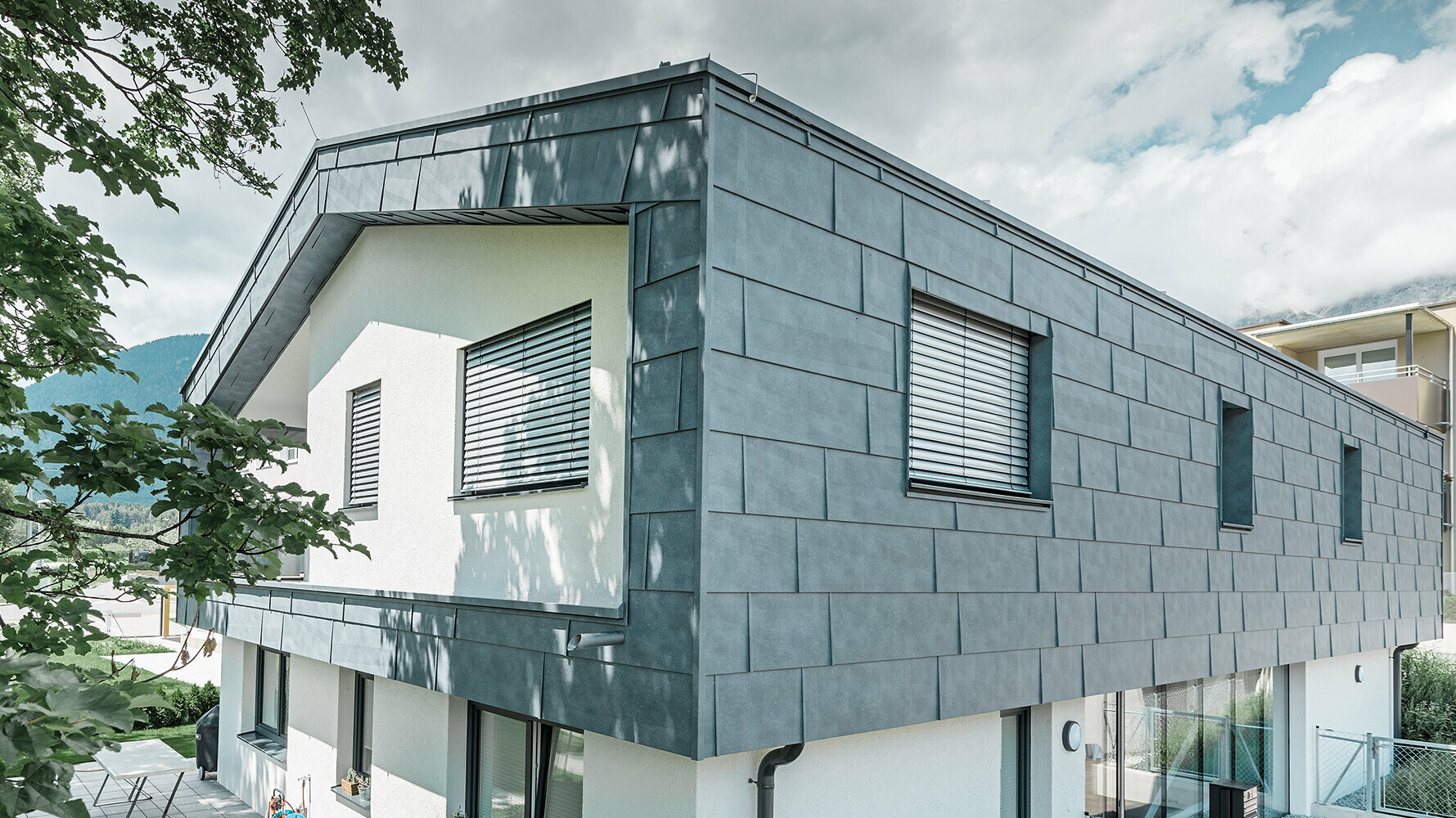 Moderne enebolig uten takutspring; Øverste etasje ble dekket med PREFA fasadepaneler FX.12 i steingrå, resten av fasaden ble pusset hvitt.