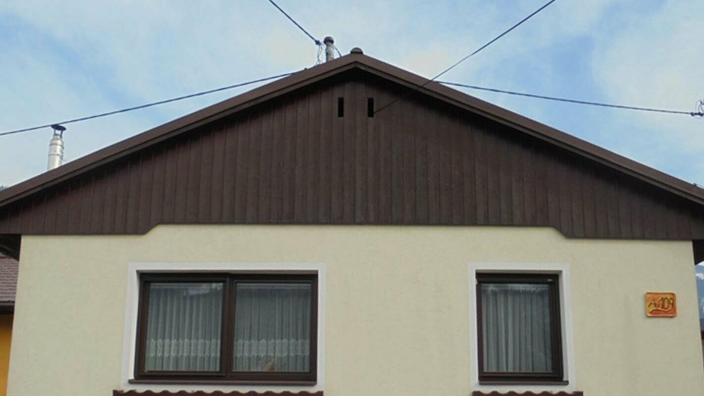 Før renovering av fasaden på gavlen med PREFA Sidings, gul pussfasade og forvitret tre