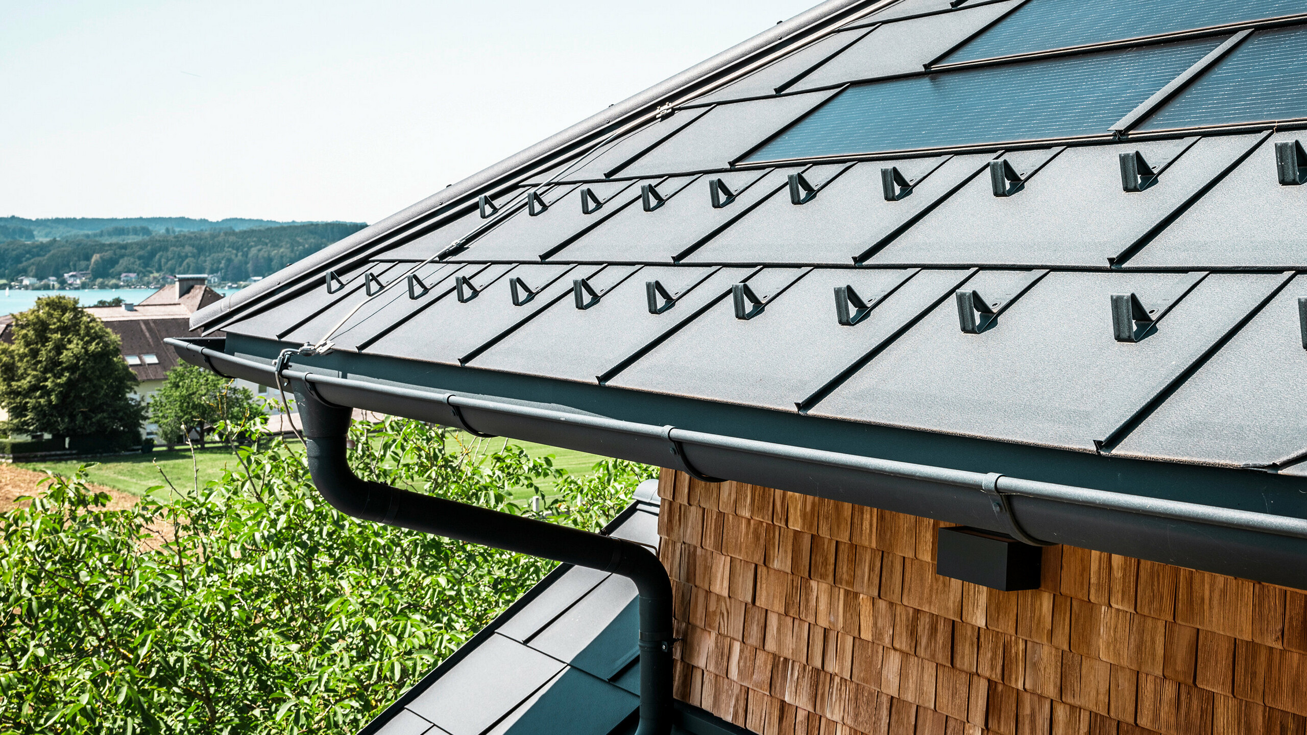 Zenz'n Stub'n i Schörfling ved Attersee har fått et nyrenoverte tak med innovative PREFA solcelle takplater og holdbare PREFA takplater R.16 i P.10 antrasitt. Det stilfulle aluminiumtaket kombinerer moderne design med bærekraftig energiproduksjon. Takdreneringen, som består av nedløpsrør og takrenne i P.10 antrasitt, passer også harmonisk inn i helhetsbildet og understreker den høye kvaliteten på utførelsen. I bakgrunnen skinner det blå Attersee.