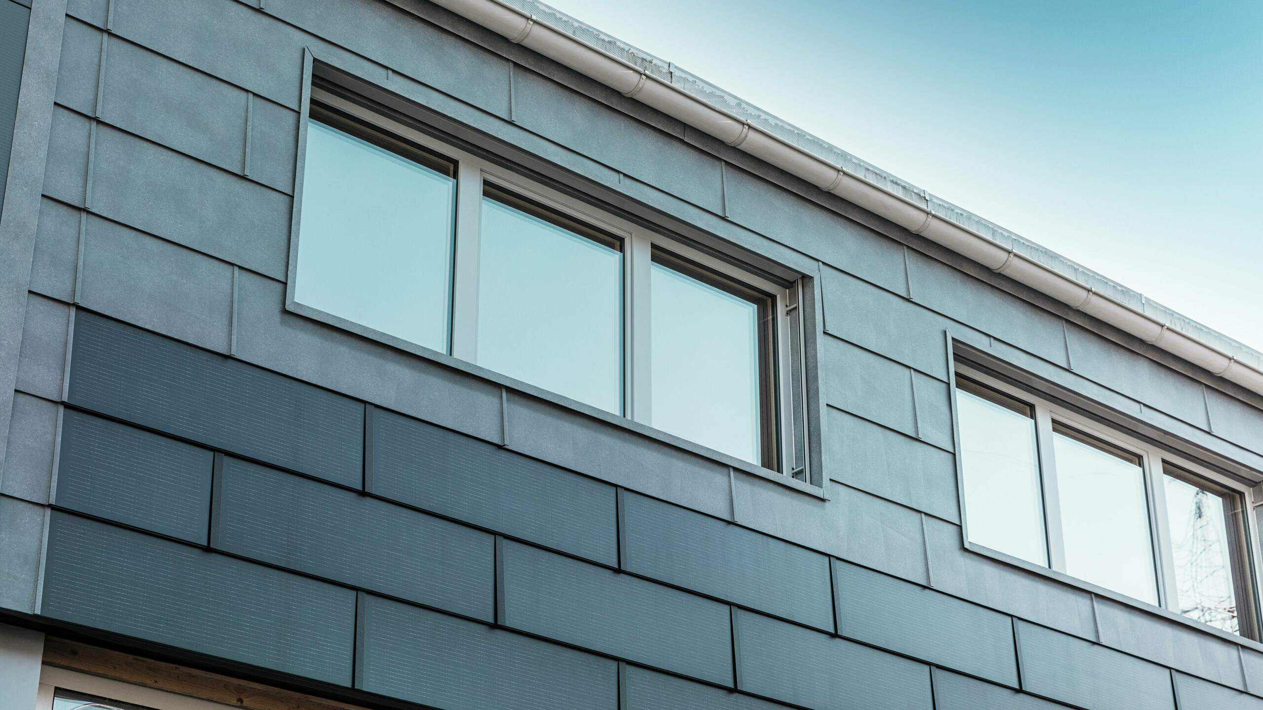 Fasadeflaten på firmaets bygning ble kledd med innovative solcelle takplate kombinert med fasadepanel FX.12 fra PREFA.