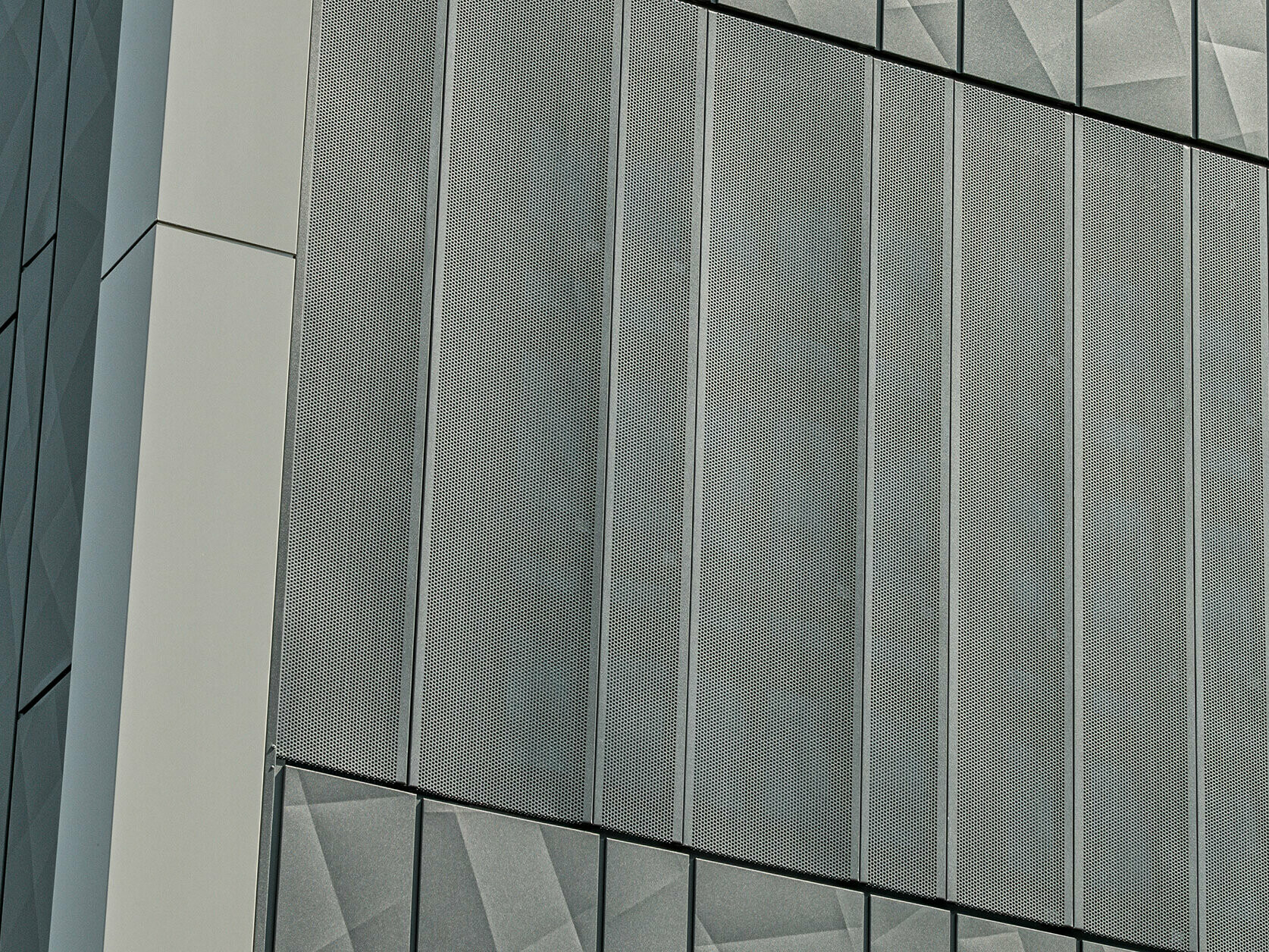 Fasadeutsikt av en Eurospar-butikk i Rohrbach med PREFA Siding.X og perforerte sidings i fargen antrasitt. Siding.X-elementene har et levende, geometrisk fugemønster, mens de perforerte Sidings gir en moderne, luftgjennomtrengelig struktur.