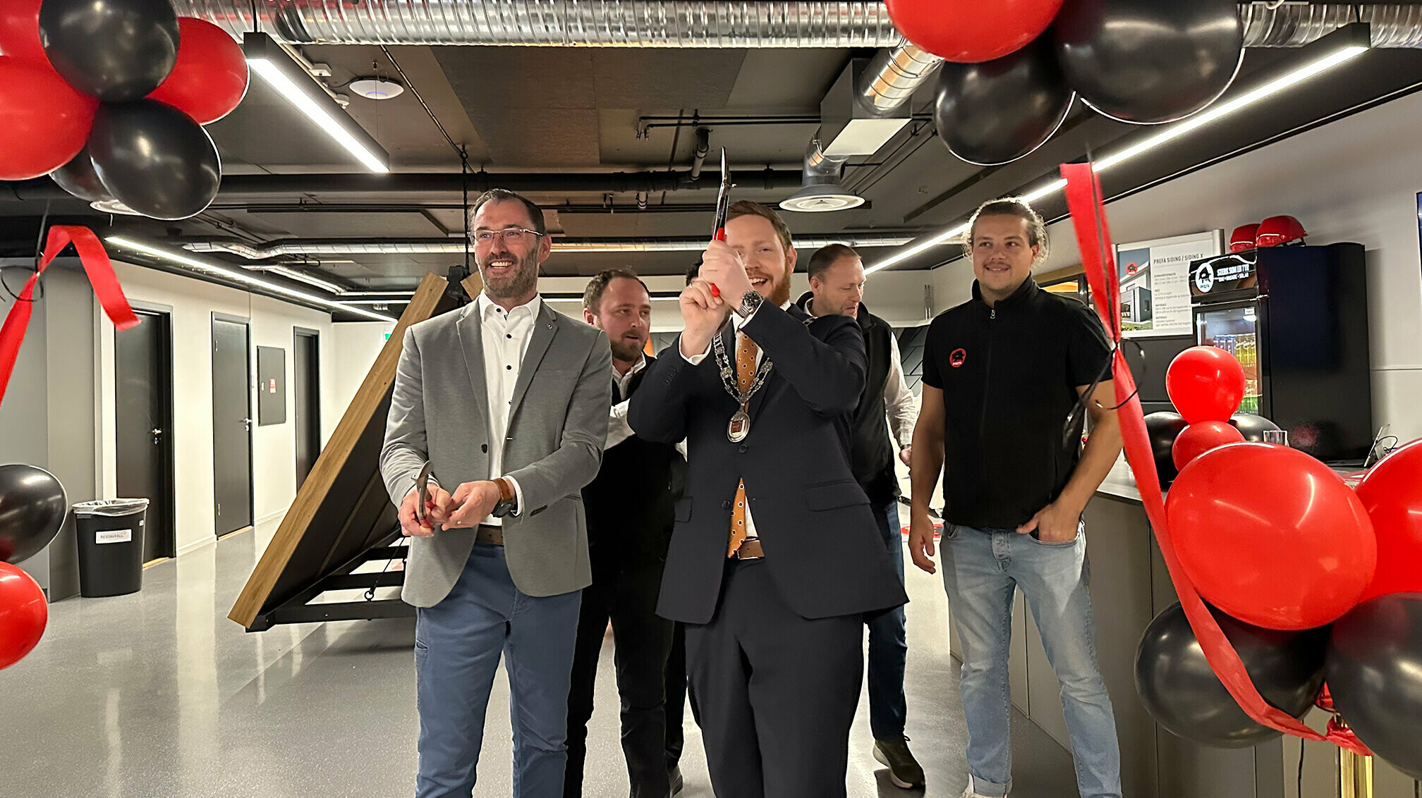 Berthold Ruck, technischer Leiter von PREFA, und der Bürgermeister von Skien beim Durchschneiden des Bandes zur feierlichen Eröffnung der PREFA Academy in Skien. Im Hintergrund sind das PREFA Academy Team aus Norwegen und PREFA Mitarbeiter zu sehen.
