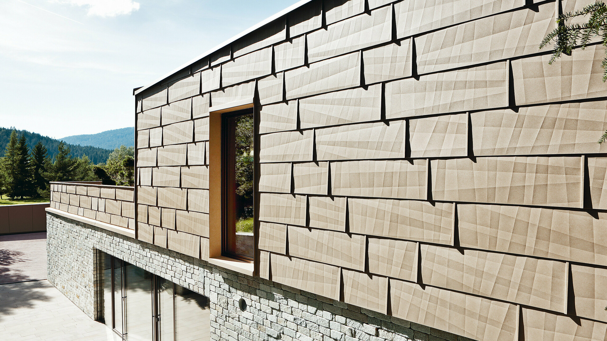 På denne utvendige fasaden ble PREFA fasadepanel FX.12 i P.10 sandbrun kombinert med en steinfasade i kjelleren.