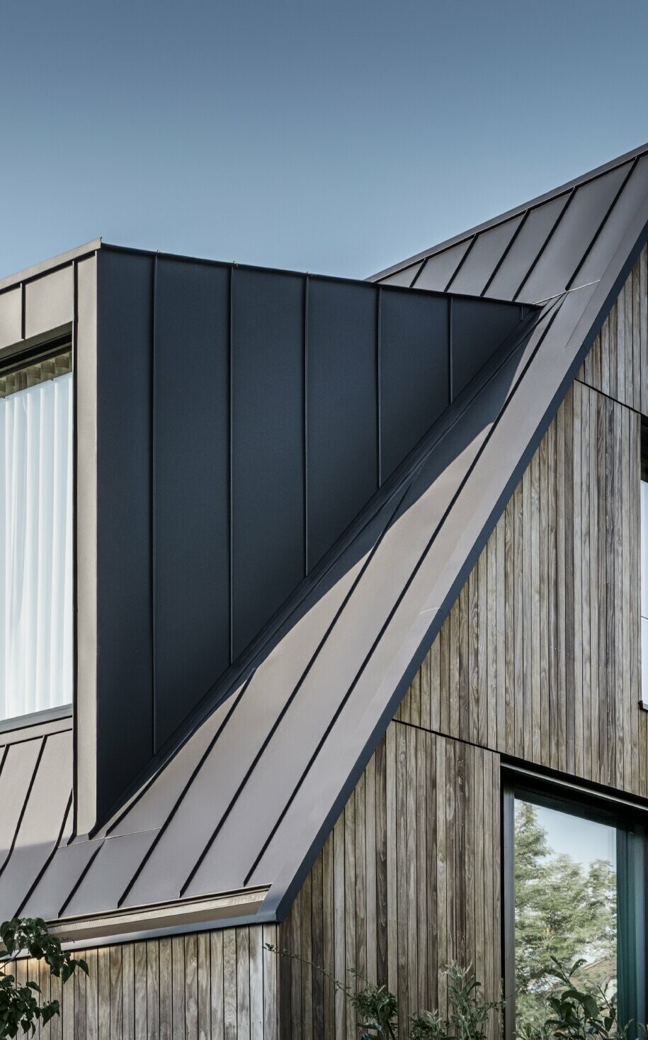 Bratt saltak med stort kvistvindu, tekket med PREFALZ fra PREFA i antrasitt, stående falstak kombinert med trefasade